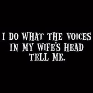 A black shirt with the words " i do what the voices in my wife 's head tell me ".