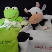 A stuffed animal frog and cow with the date of birth.