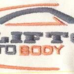 A white shirt with an orange and blue car on it