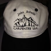 A white hat with black trim and the name john schultz carpentry llc