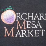 A close up of the logo for orchard mesa market