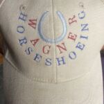 Beige baseball cap embroidered "Wagner Horseshoeing" logo