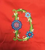 Embroidered floral letter D on red fabric