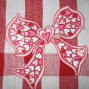 Embroidered pink heart-patterned bow on gingham