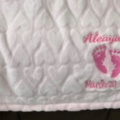Quilted baby blanket with embroidered pink footprints