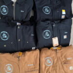Folded Carhartt work jackets with embroidered patches