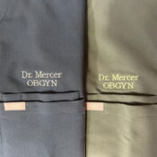 Two scrubs embroidered "Dr Mercer OBGYN