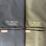 Two scrubs embroidered "Dr Mercer OBGYN