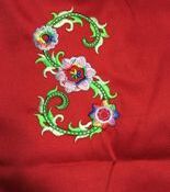 Embroidered floral letter S on red fabric