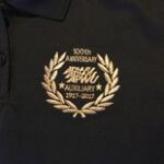 Gold laurel 100th anniversary embroidery on black polo