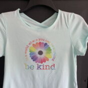 Light blue t-shirt with rainbow daisy "be kind