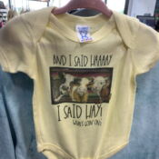 A baby onesie with a picture of cows on it.