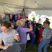 Shoppers browsing clothing racks in festival tent