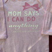 Pink baby onesie with bow and slogan