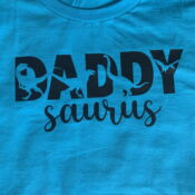 Teal t-shirt printed "DADDY saurus" with dinosaurs