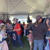 Shoppers browsing clothes inside outdoor vendor tent