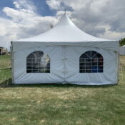 A white tent with windows in the middle of a field.