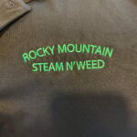 Black shirt embroidered 'Rocky Mountain Steam N'Weed' logo
