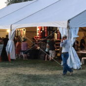 People browsing vendor booths under white tent