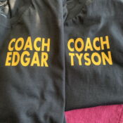 A pair of black coach jackets with yellow lettering.